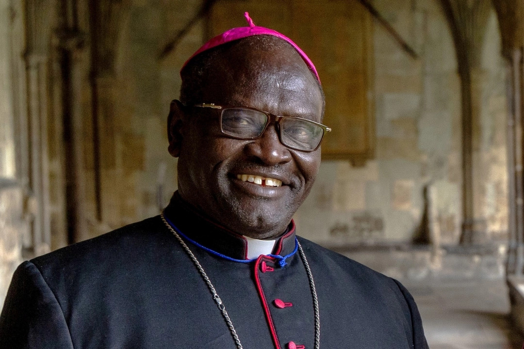 Der Bischof von Darfur steht im gotischen Kreuzgang einer Kirche.