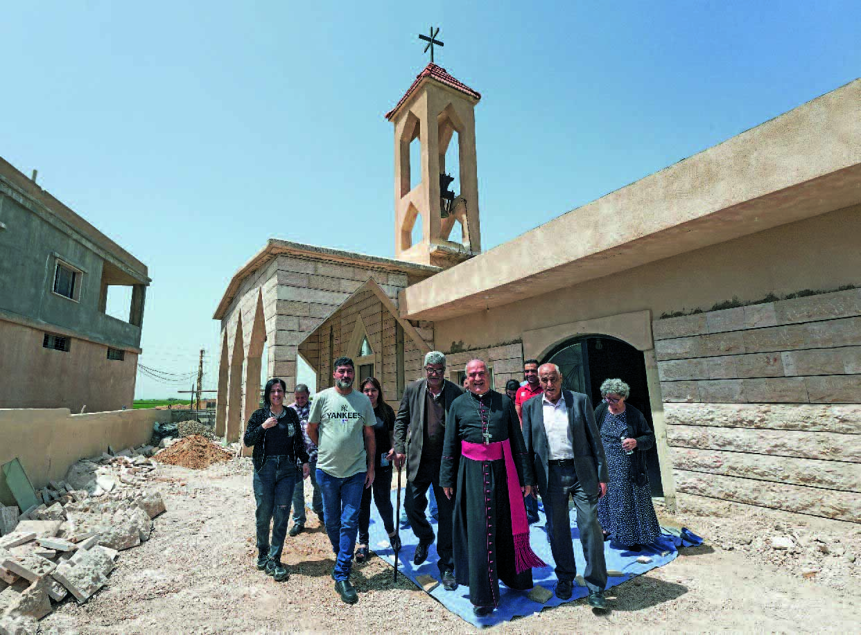 Ein Erzbischof und eine Gruppe von Menschen kommt aus einer Kirche heraus.