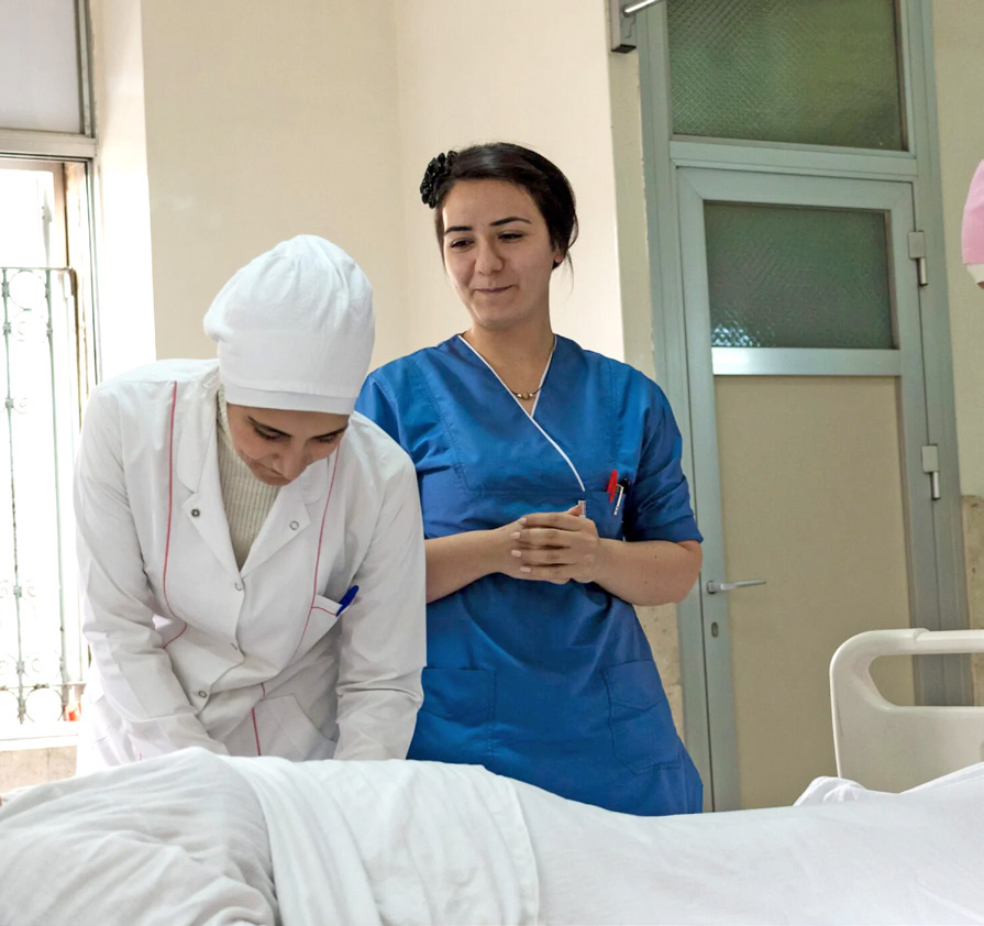 Zwei Krankenschwestern am Bett eines Patienten.