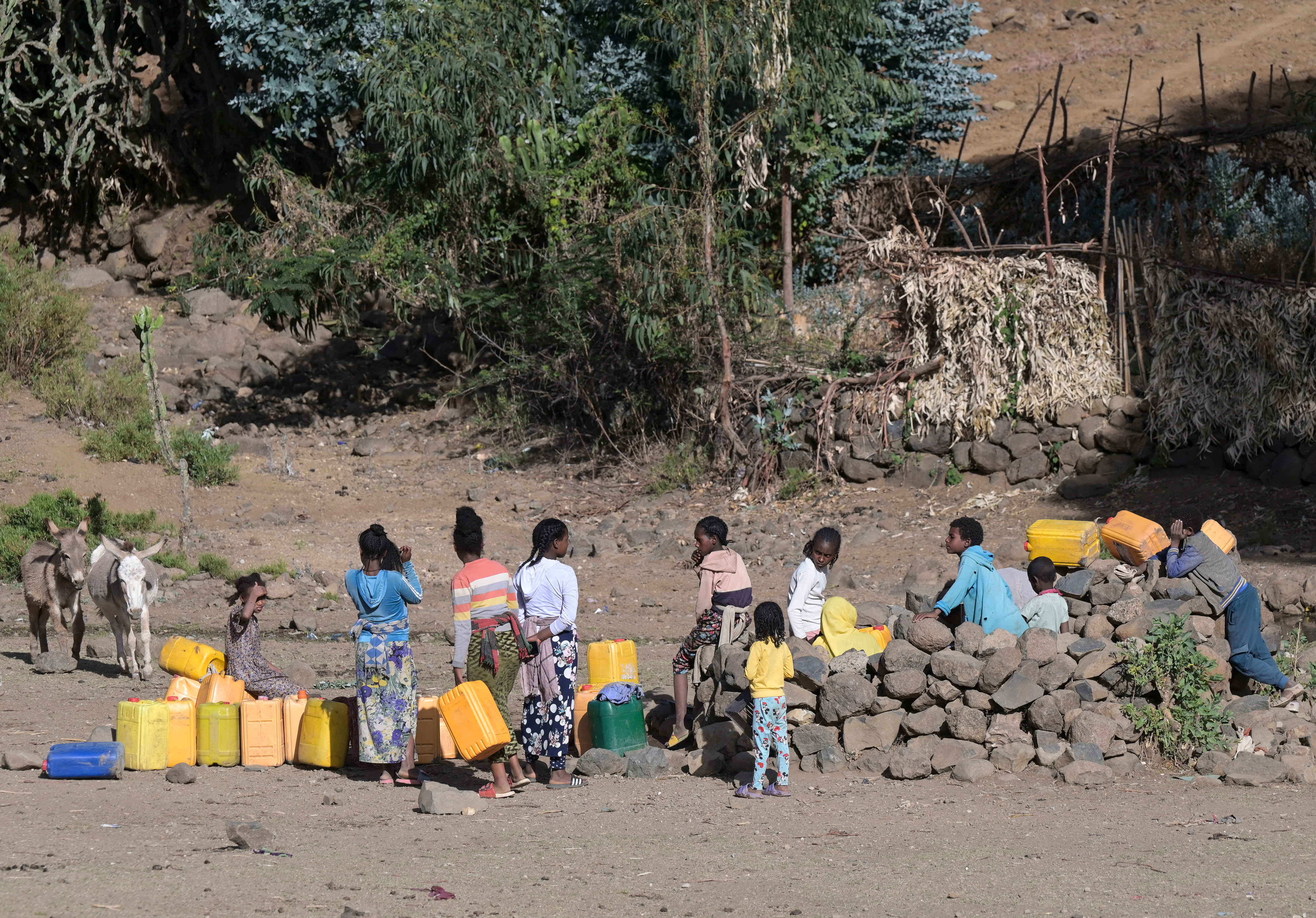 Mädchen und junge Frauen warten an einer Wasserstelle mit ihren Kanistern