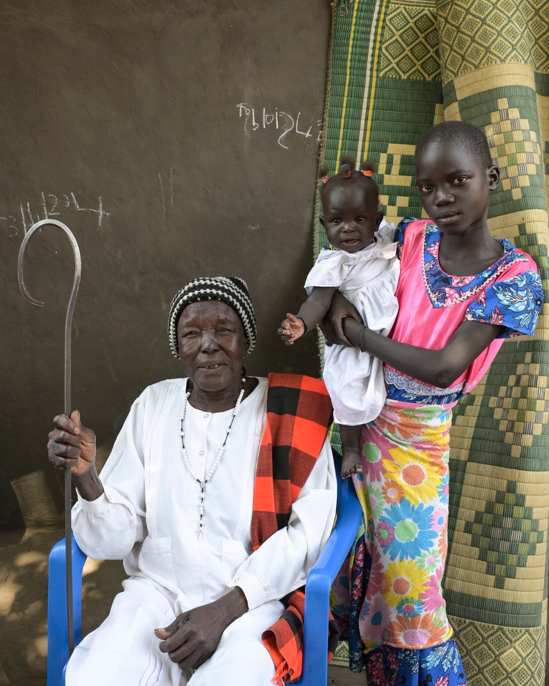 Der Titel des missio magazin 04/2026 zeigt drei Generationen von Frauen aus Uganda: ganz links sitzt eine alte Frau in weißer Kleidung mit Stab als Zeichen ihrer Würde, neben ihr eine Heranwachsende, die auf dem Arm ein Baby hält.