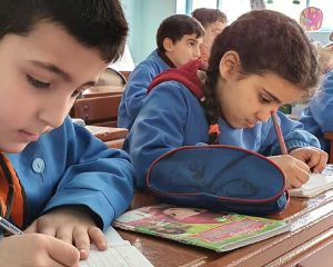 Kinder sitzen in Schulbänken und schreiben